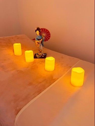 Massage table with lit candles and a geisha figurine.