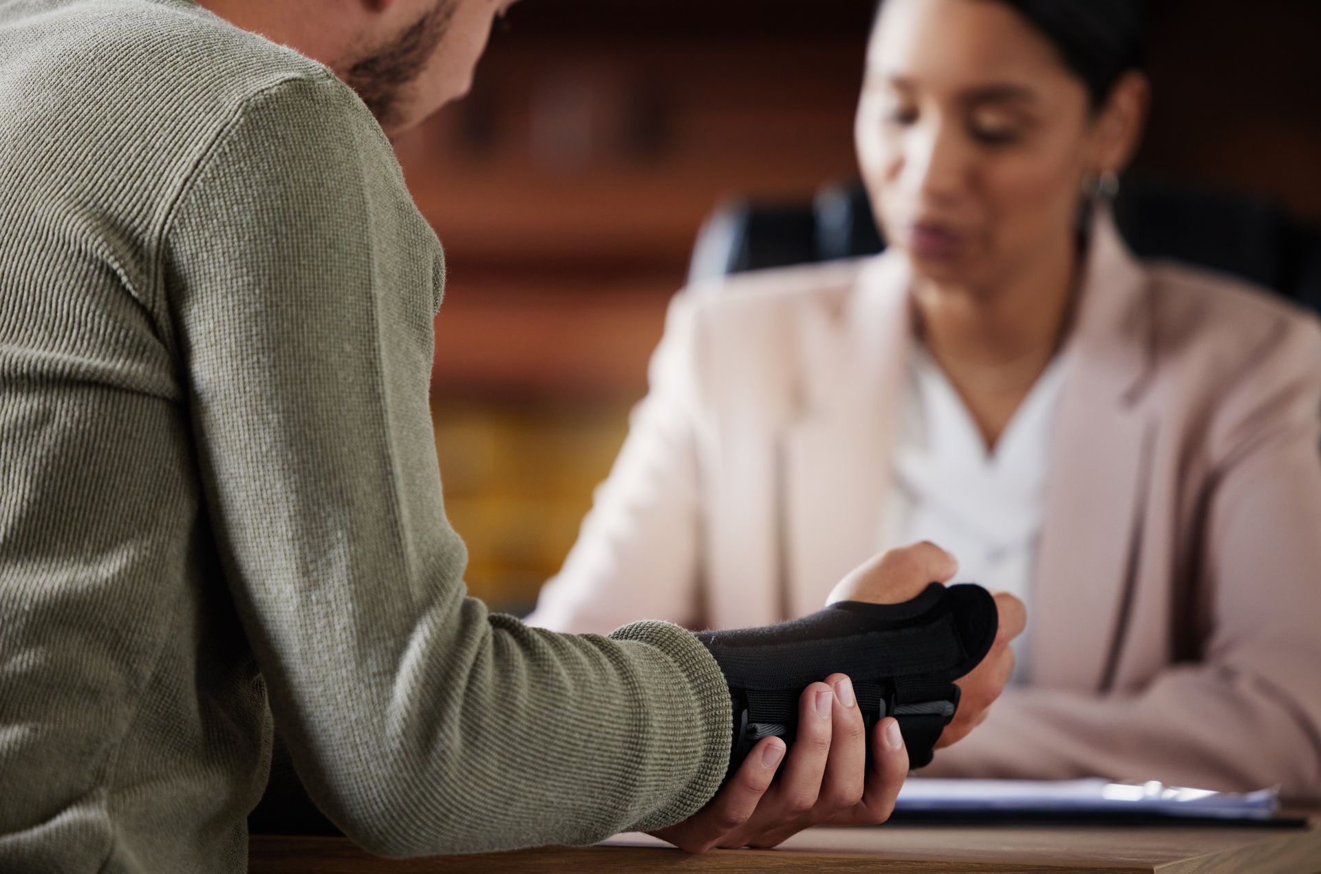 Injured worker wearing a wrist brace consulting with an attorney across a desk