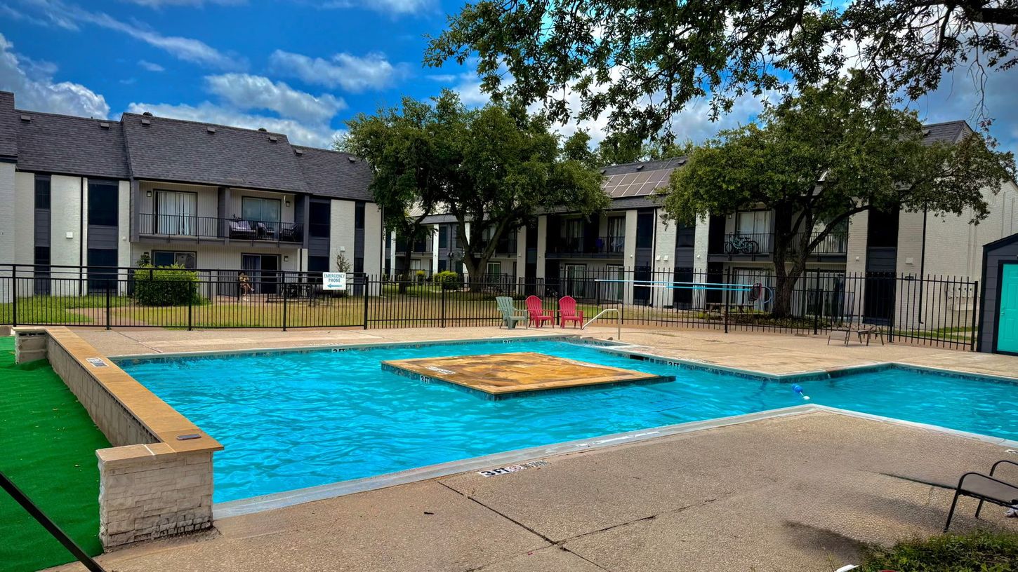 Swimming pool in front of apartment buildings on a sunny day.