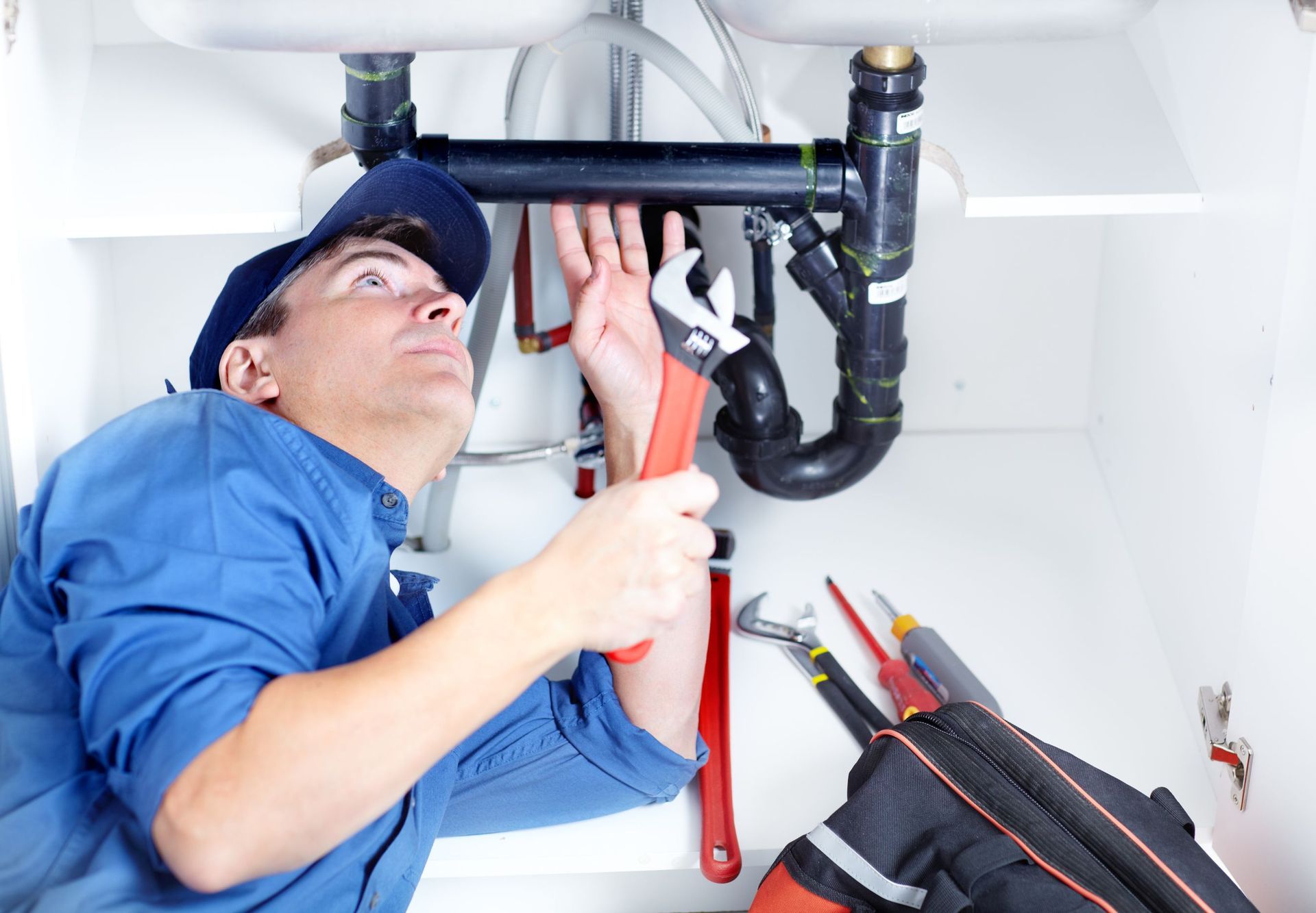 handsome professional plumber doing sink reparation