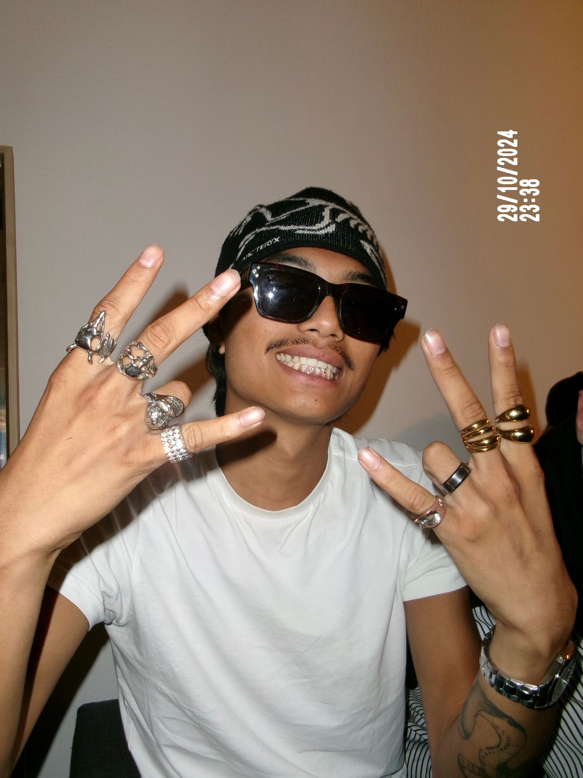 Un garçon en chemise bleue regarde l'objectif, avec des aras bleus et jaunes perchés sur des branches.