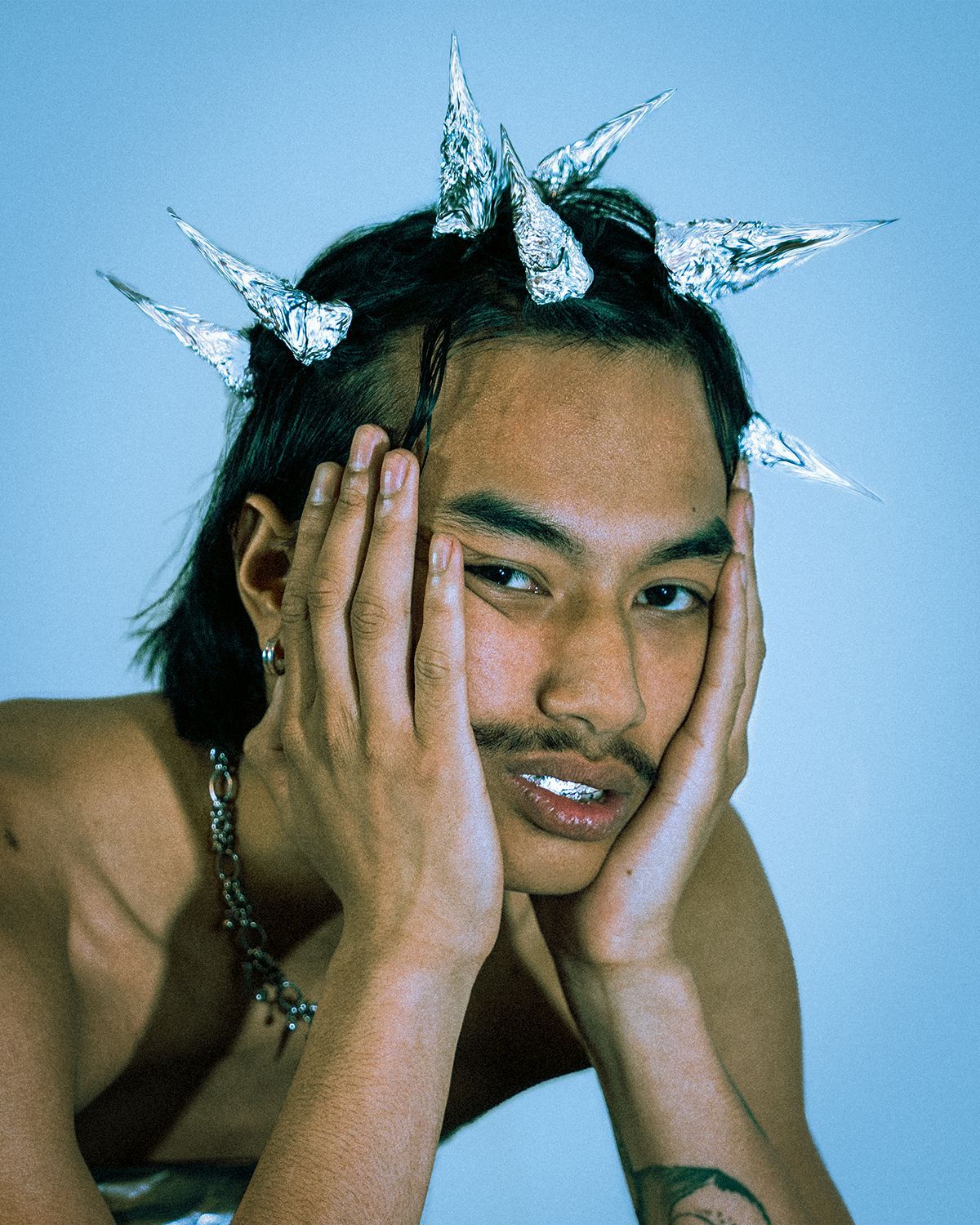 Un homme vêtu de noir et portant une écharpe se tient devant une œuvre d'art abstrait dans une galerie.