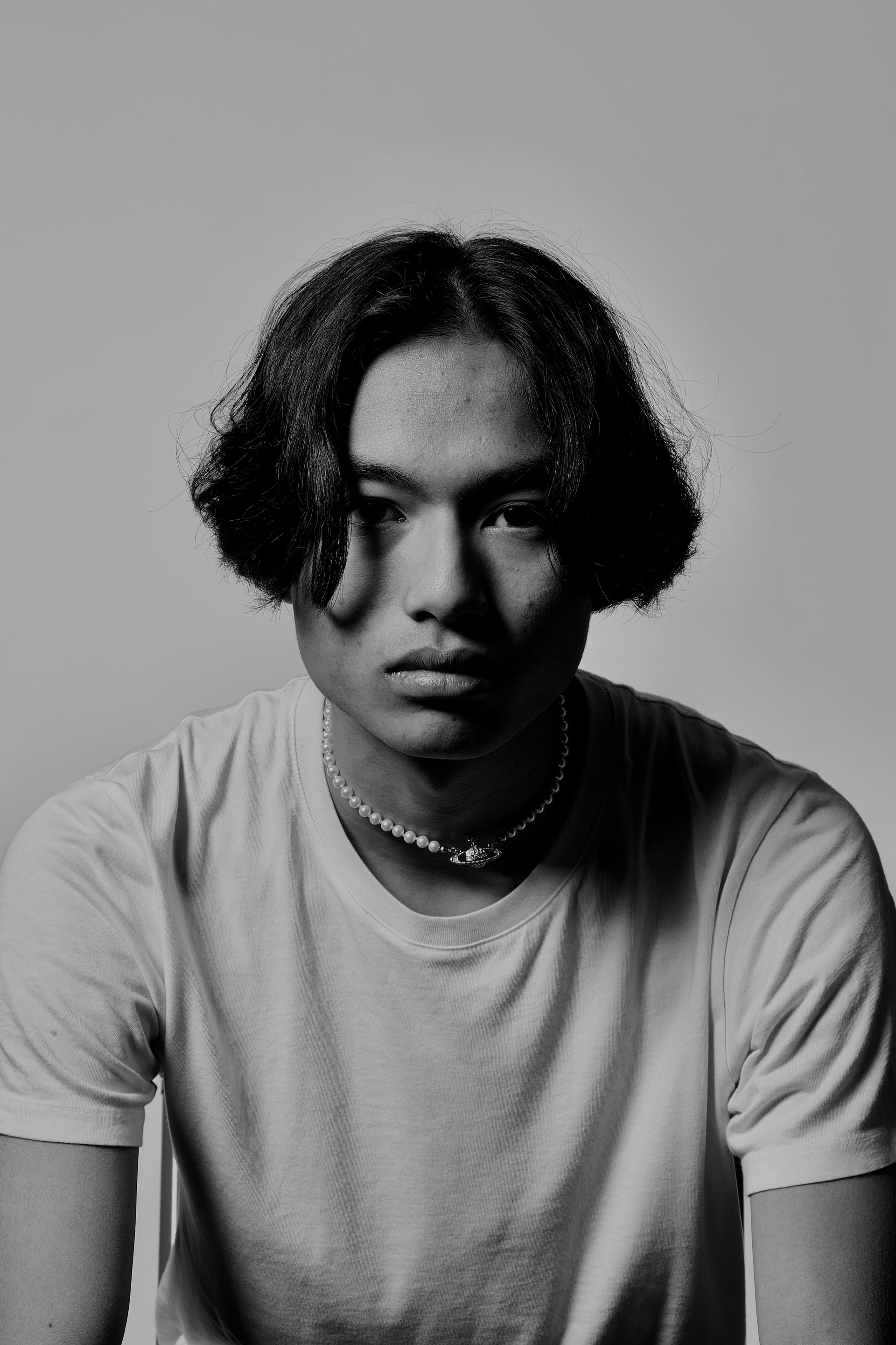 Une personne pose à l'intérieur d'un cadre rouillé, sur une colline surplombant une ville. Ciel bleu et mer en arrière-plan.