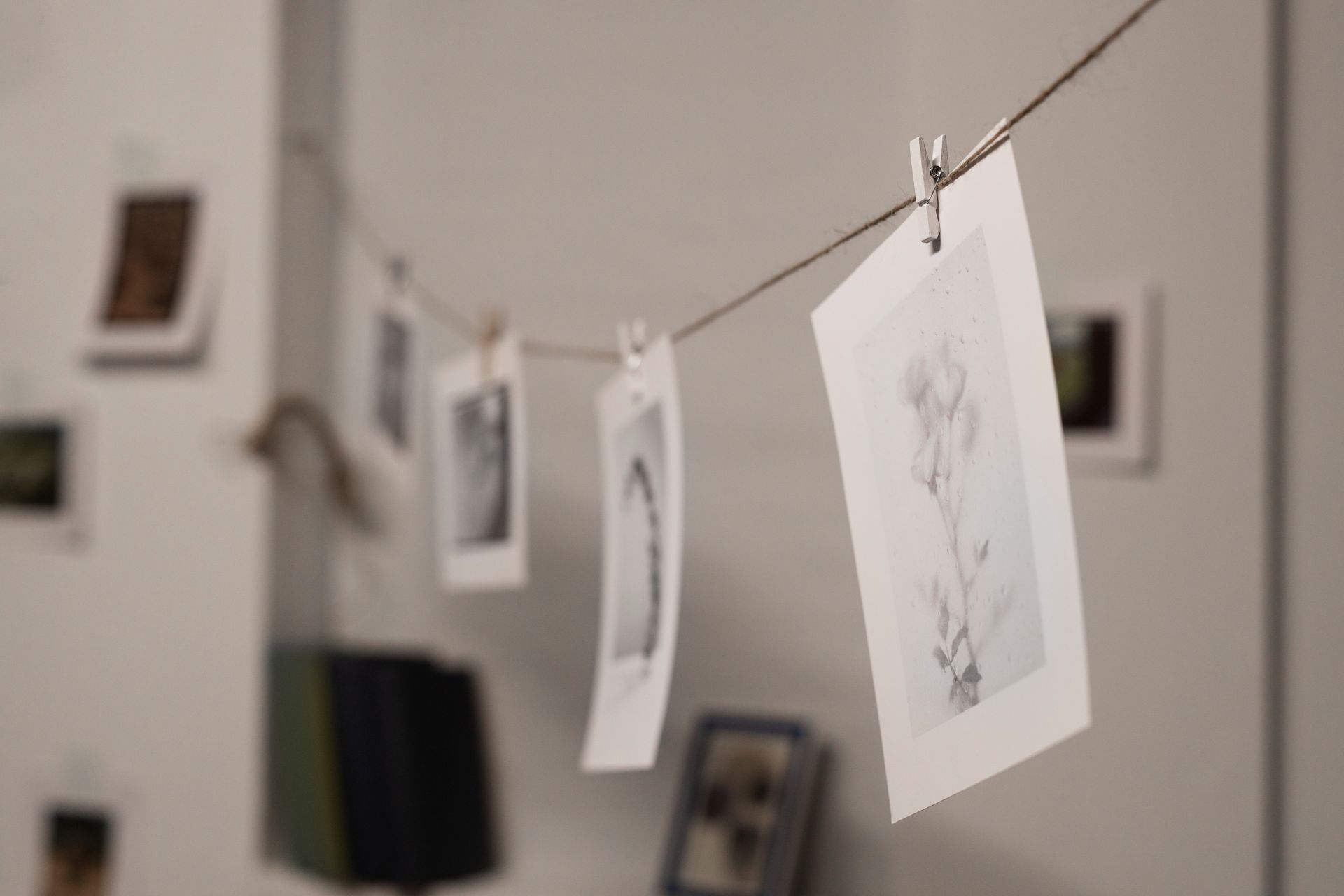 Des photographies sont suspendues à une ficelle à l'aide de pinces à linge ; mur blanc en arrière-plan.