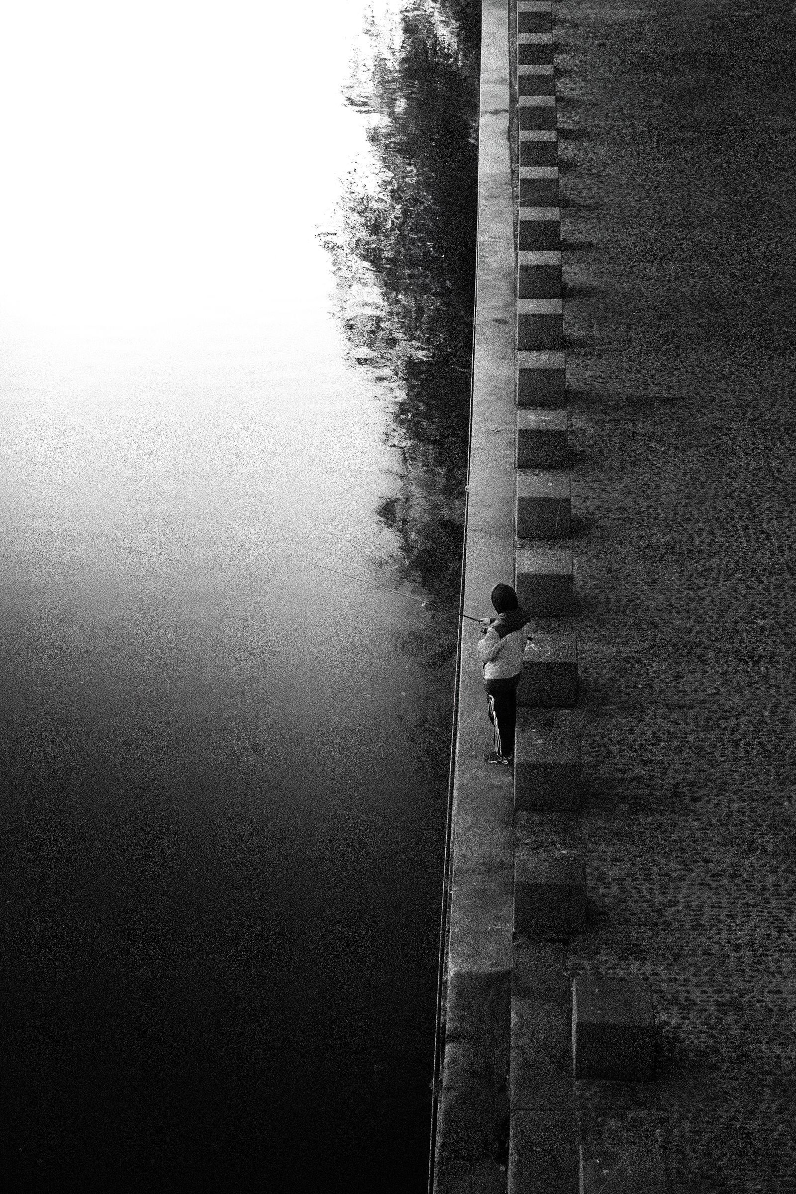 Une personne debout sur un haut mur à gradins, des arbres en arrière-plan, un ciel brumeux.