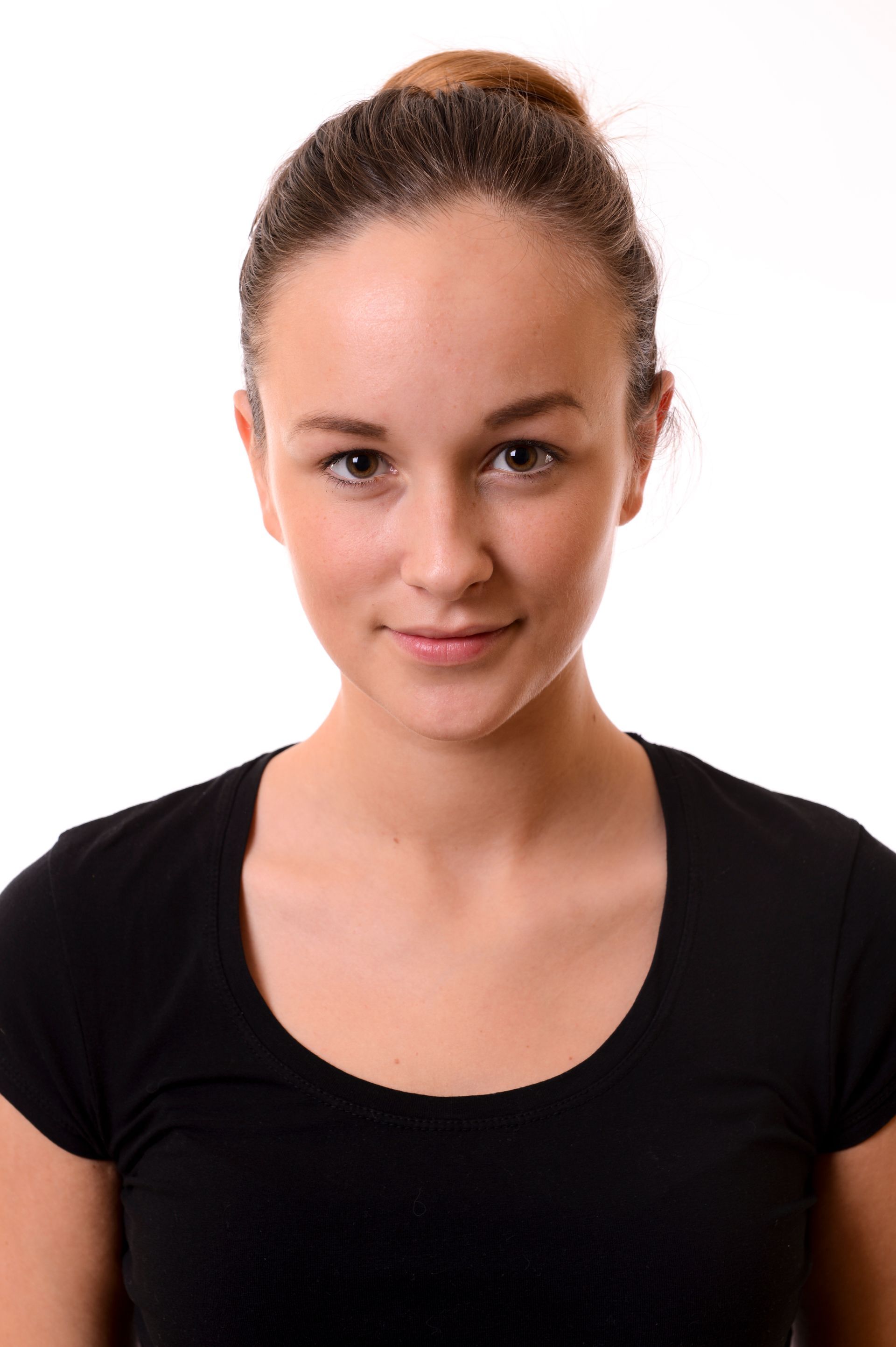 Femme aux cheveux relevés en chignon, vêtue d'un t-shirt noir, regardant l'objectif. Fond blanc.