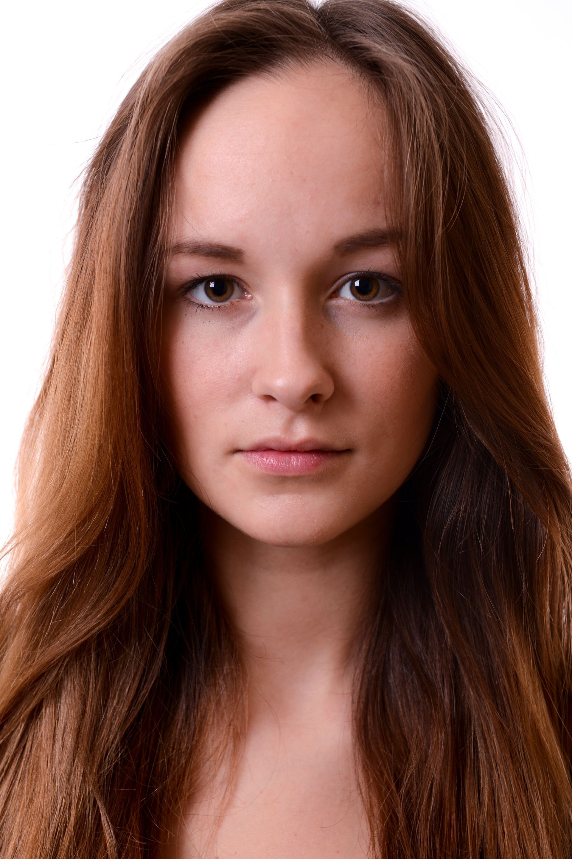 Femme aux longs cheveux bruns, regardant droit dans l'objectif avec une expression neutre, sur fond blanc.