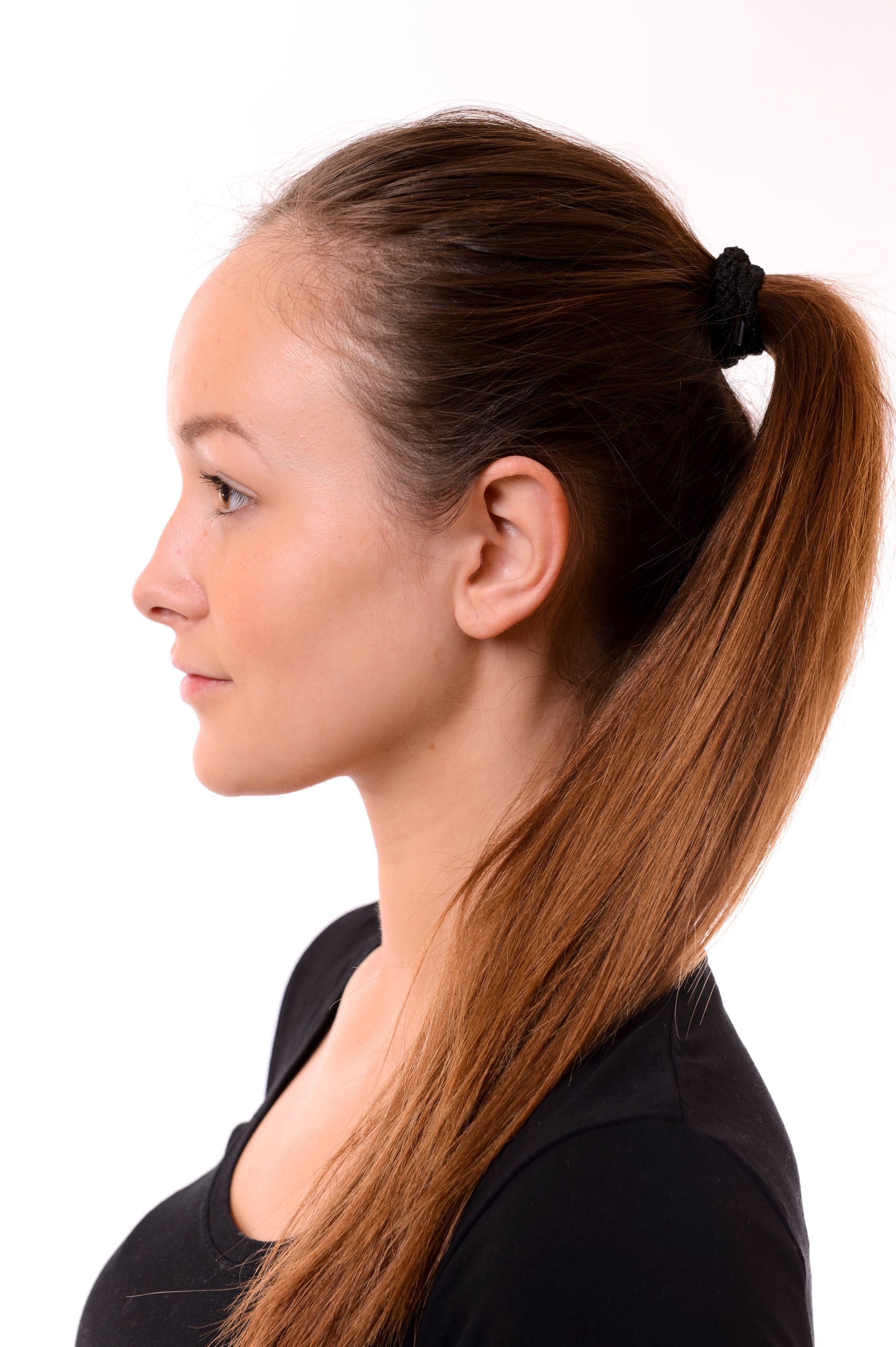 Femme aux cheveux bruns coiffés en queue de cheval, portant un chemisier noir, regardant vers la gauche.