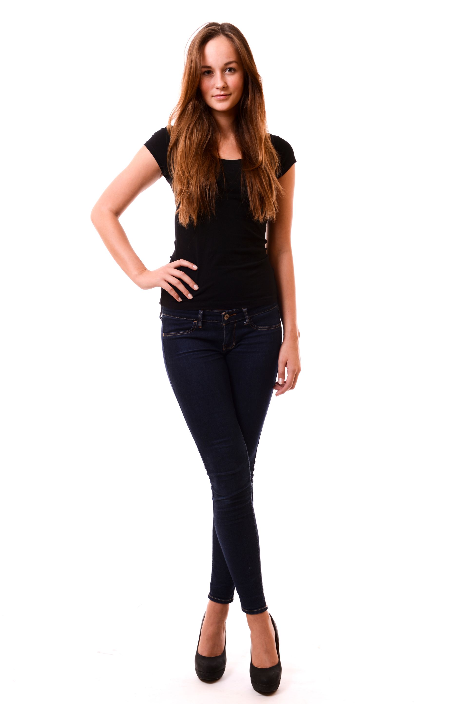 Femme en haut noir et jean, main sur la hanche, souriante.