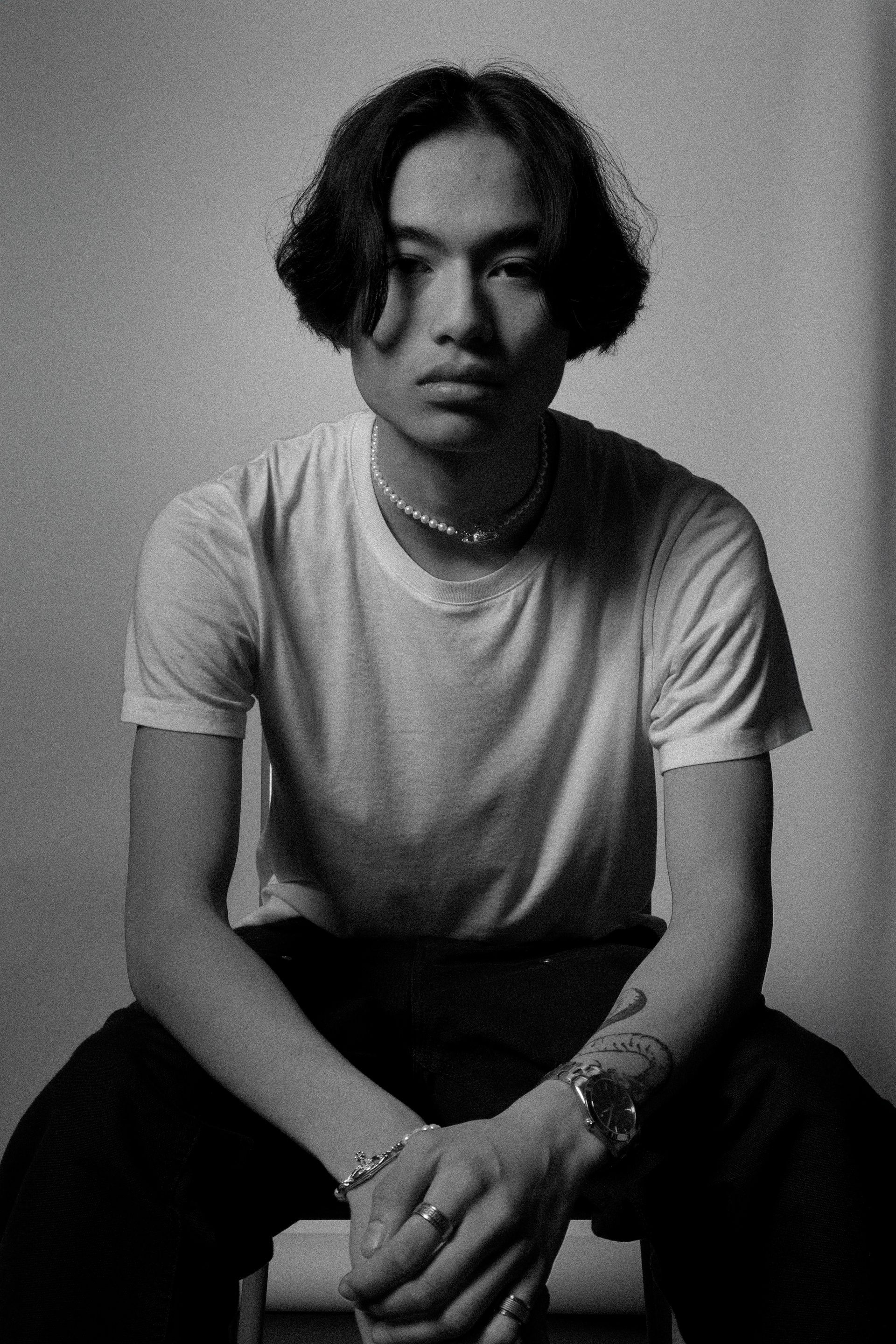 Homme aux cheveux foncés et à la chemise blanche, assis, regardant droit devant lui.