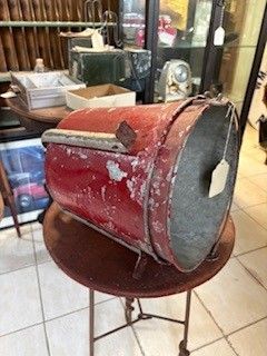 Red metal container on a small table. Silver rim and handle. White price tag hanging.