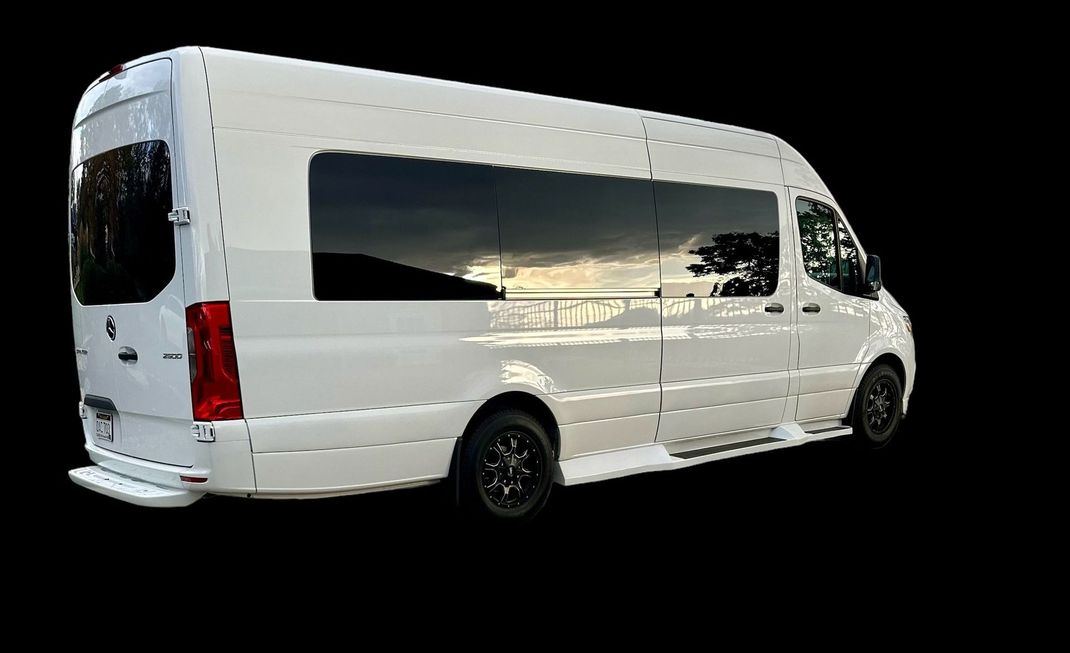 A white van with a lot of windows is parked on a black background.