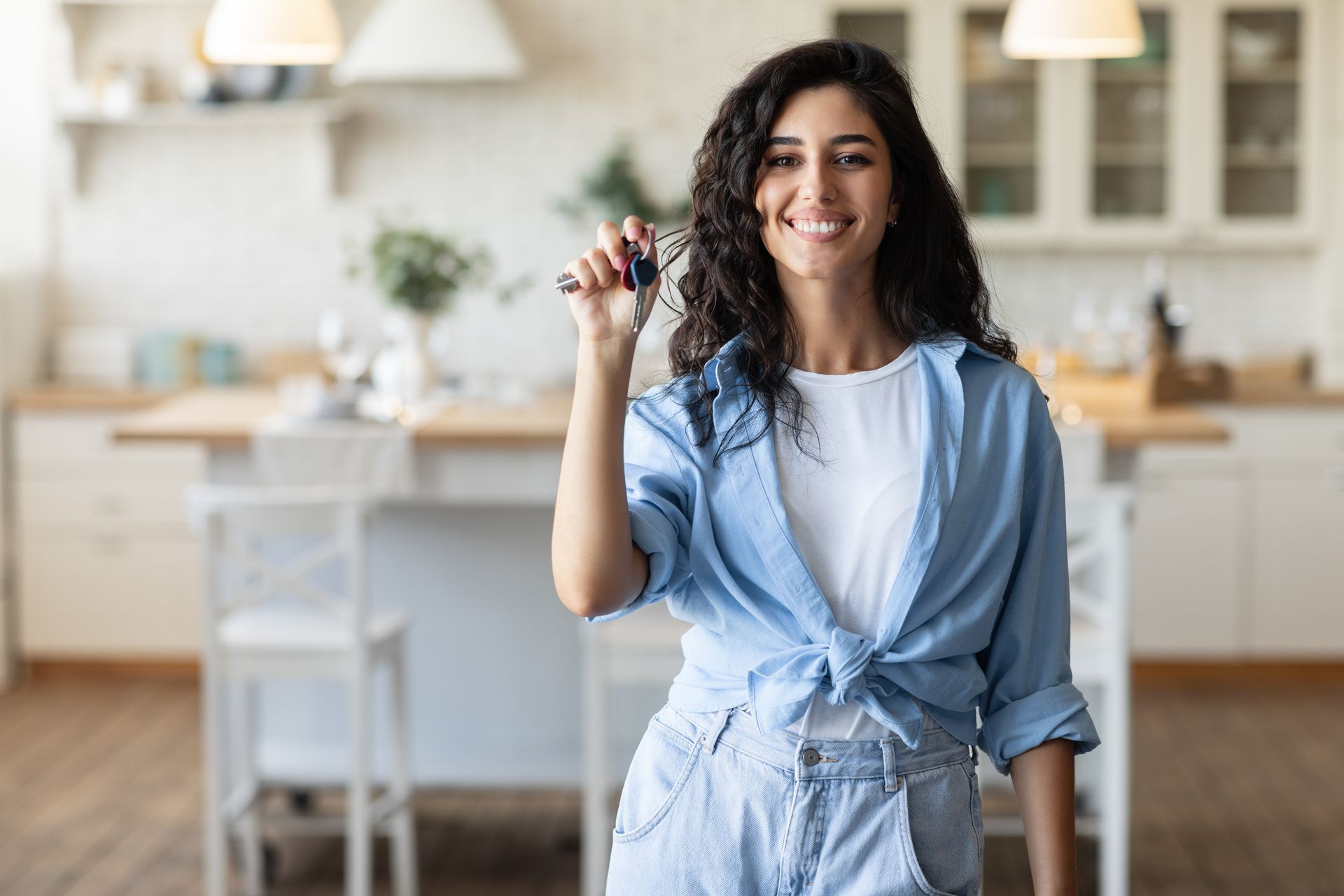 A woman is holding a key in her hand in a kitchen.