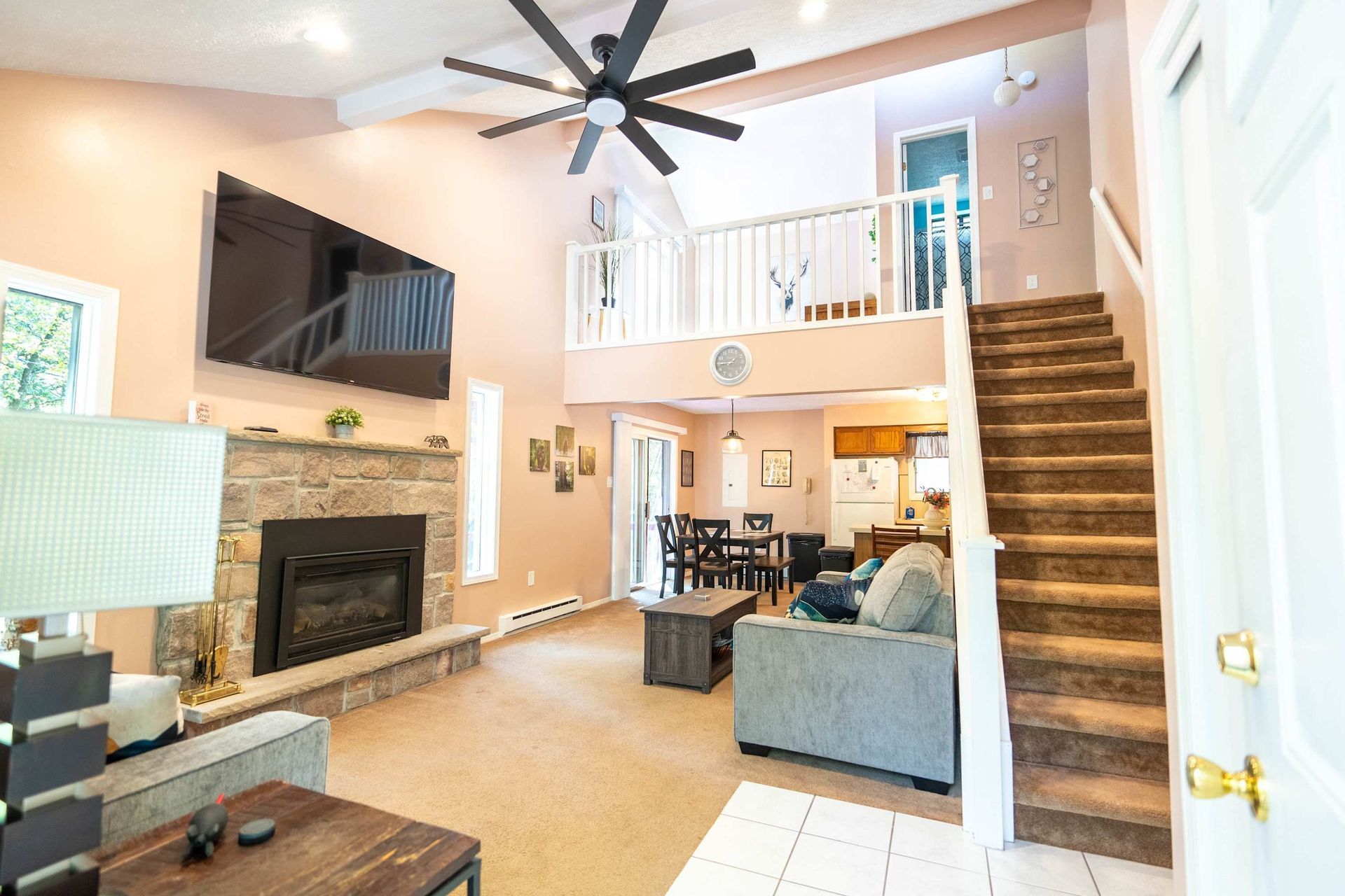 A living room with a fireplace , stairs and a flat screen tv.