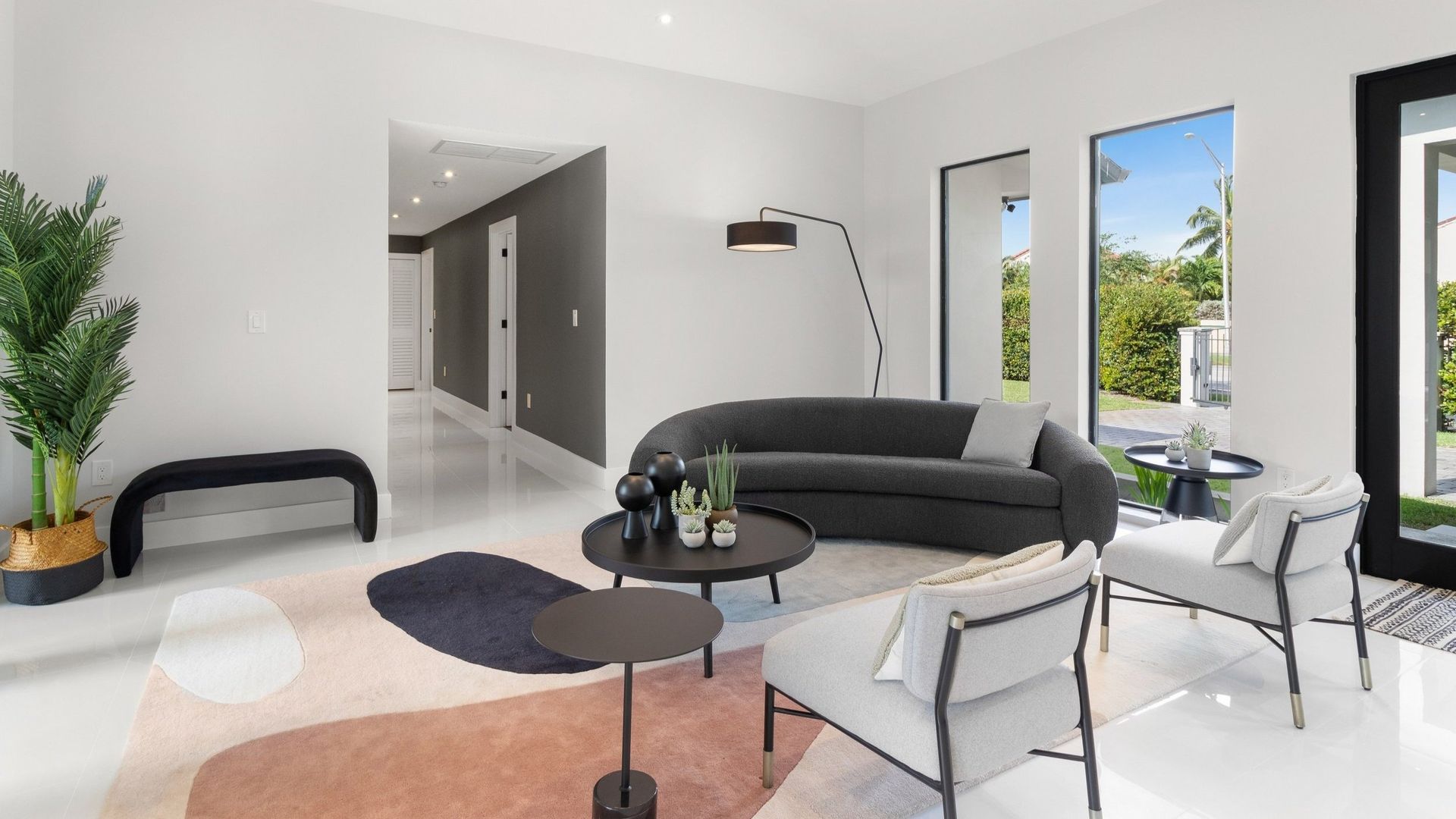 A living room with a couch , chairs , tables and a rug.