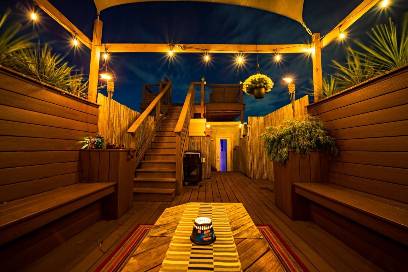 A wooden deck with a table and benches at night.