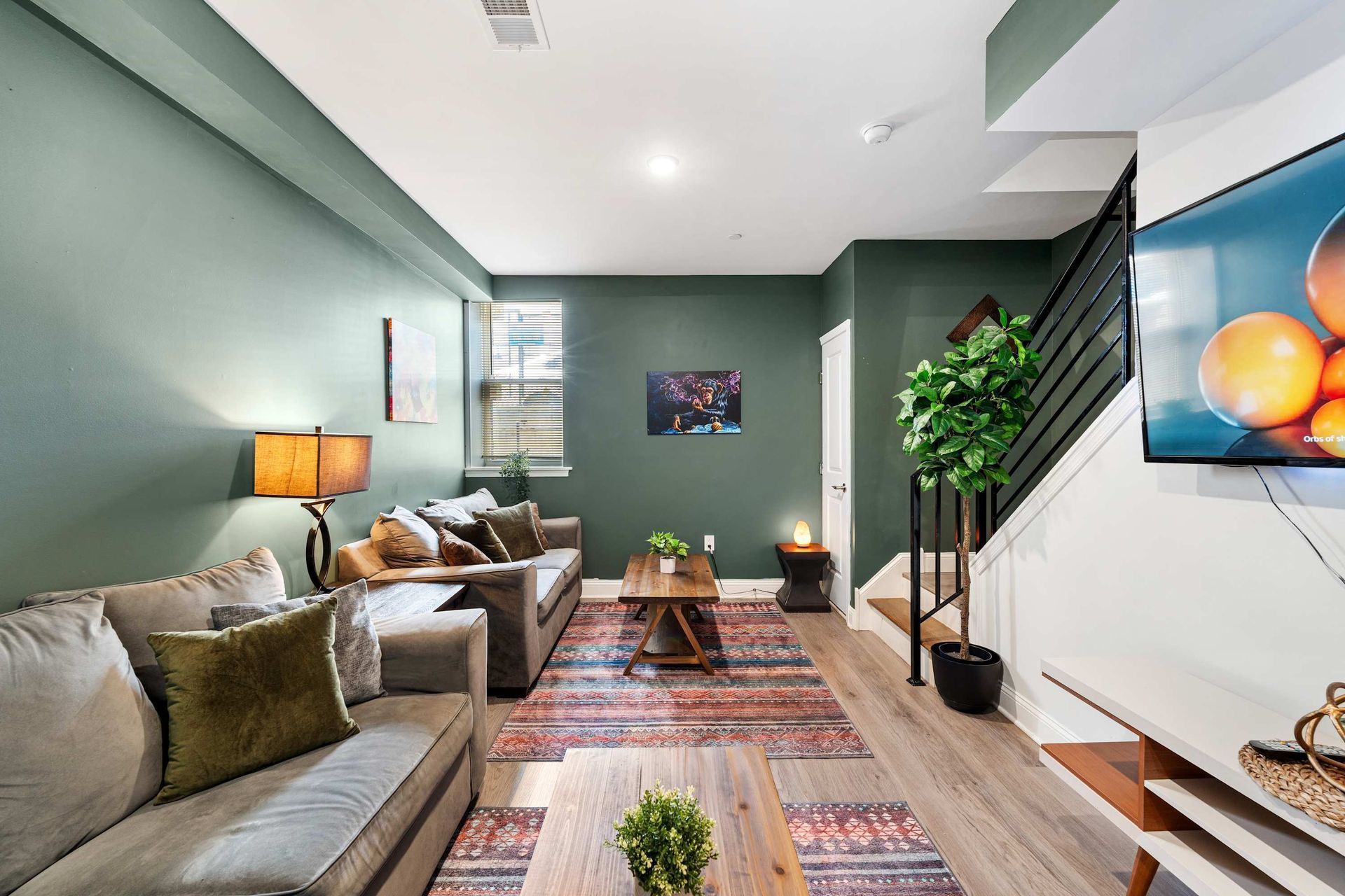 A living room with a couch , coffee table , television and stairs.