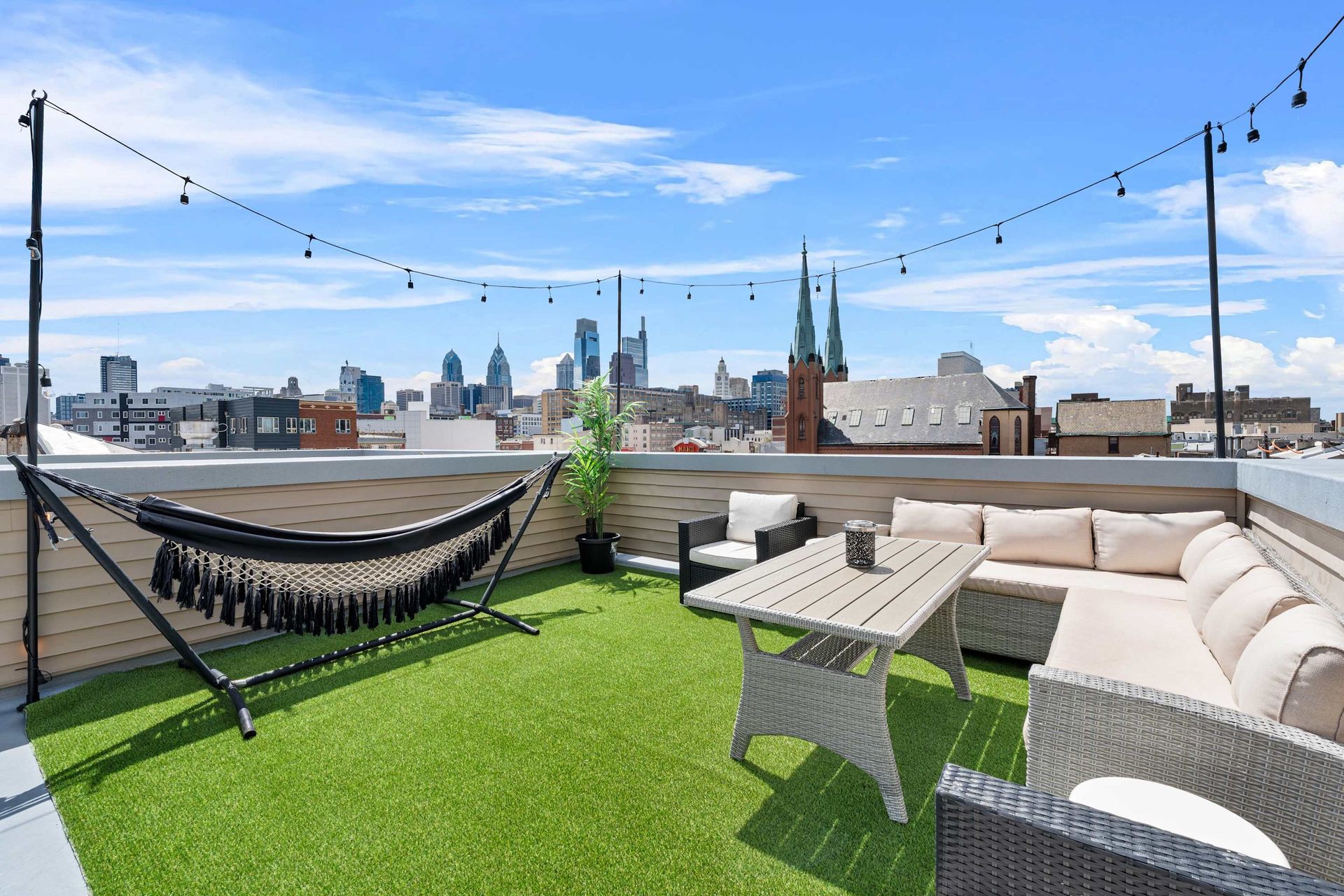 A rooftop patio with a hammock , couch , table and chairs.