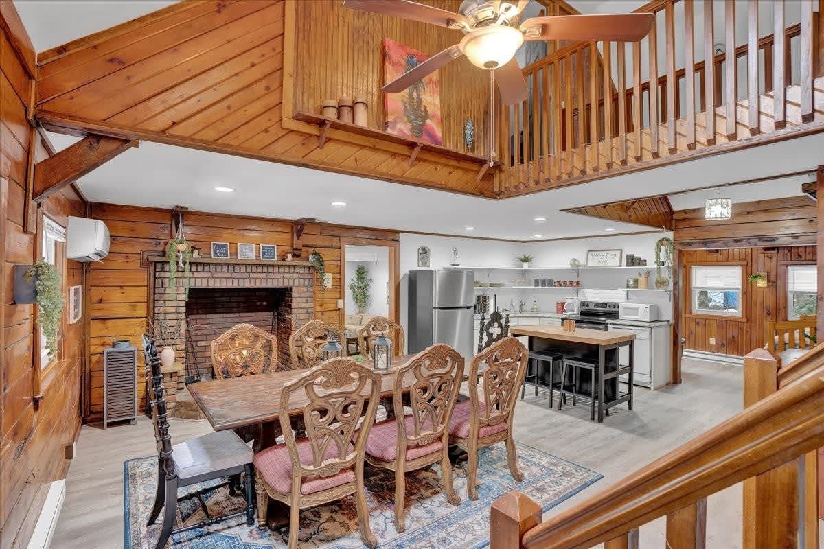 A large wooden house with a dining room table and chairs and a fireplace.