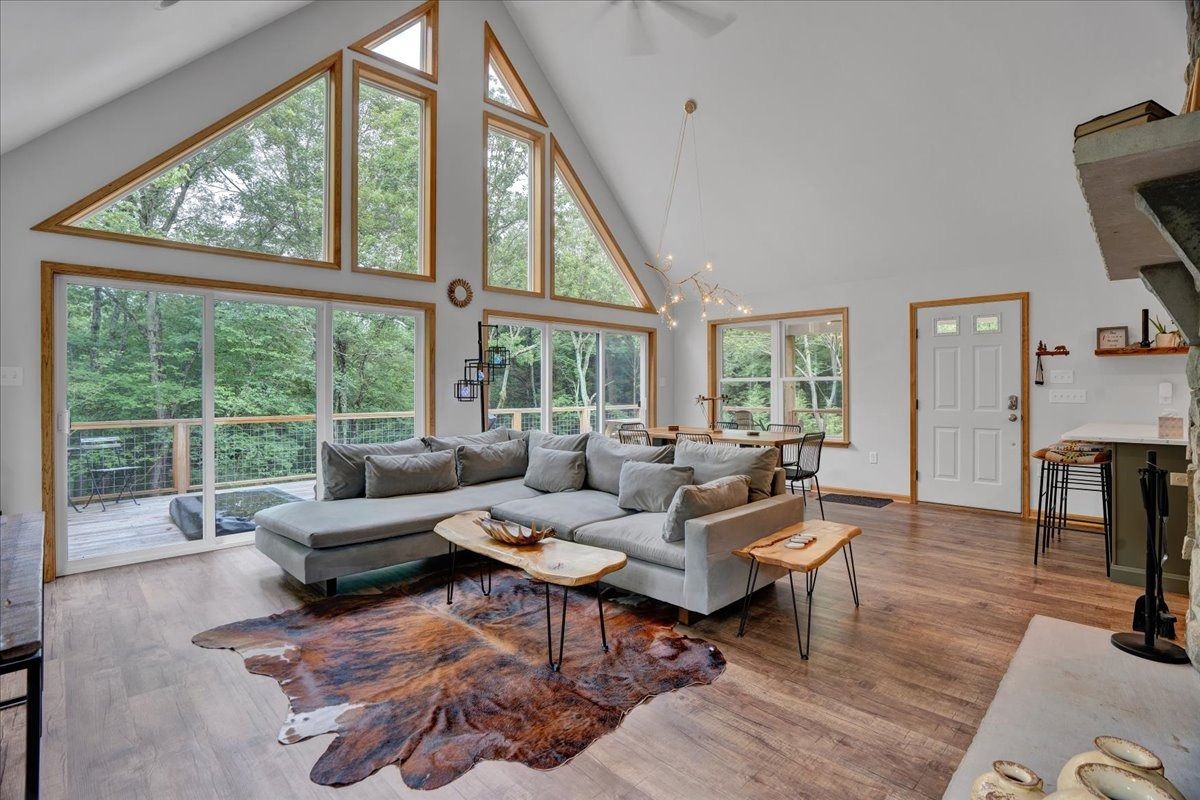A living room with a couch , rug , and lots of windows.