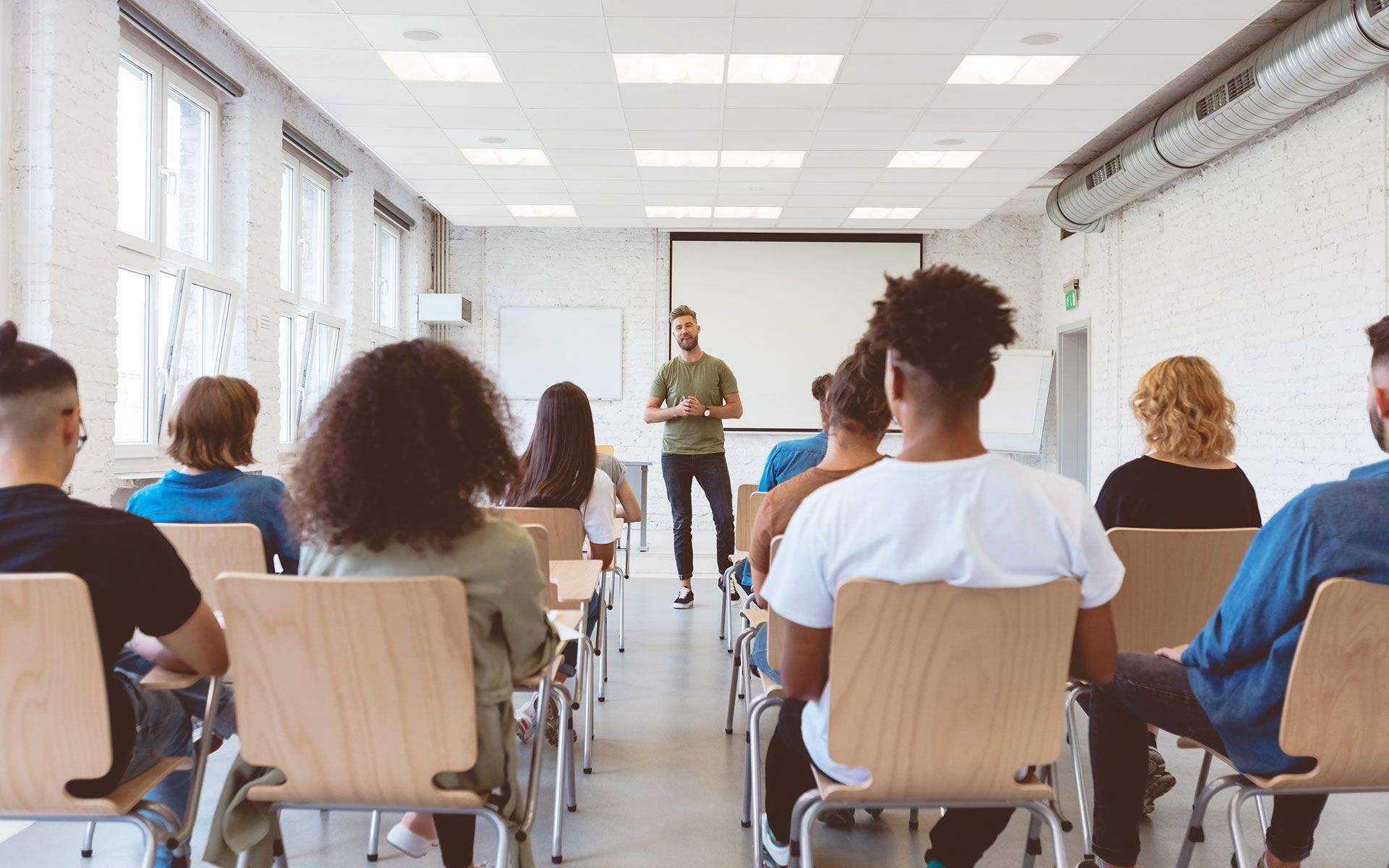 A man is giving a presentation to a group of people in a classroom.