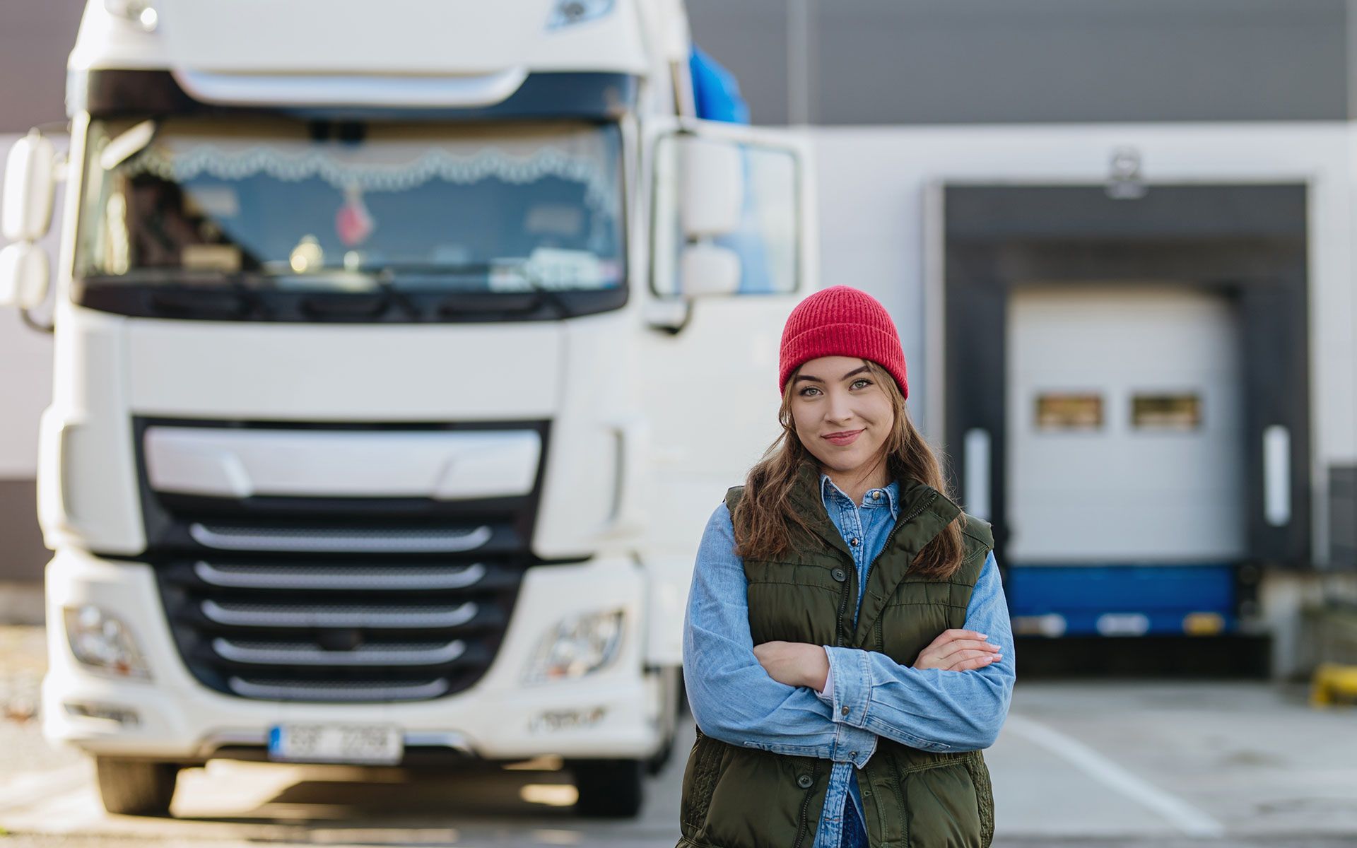 A woman is standing in front of a truck with her arms crossed.