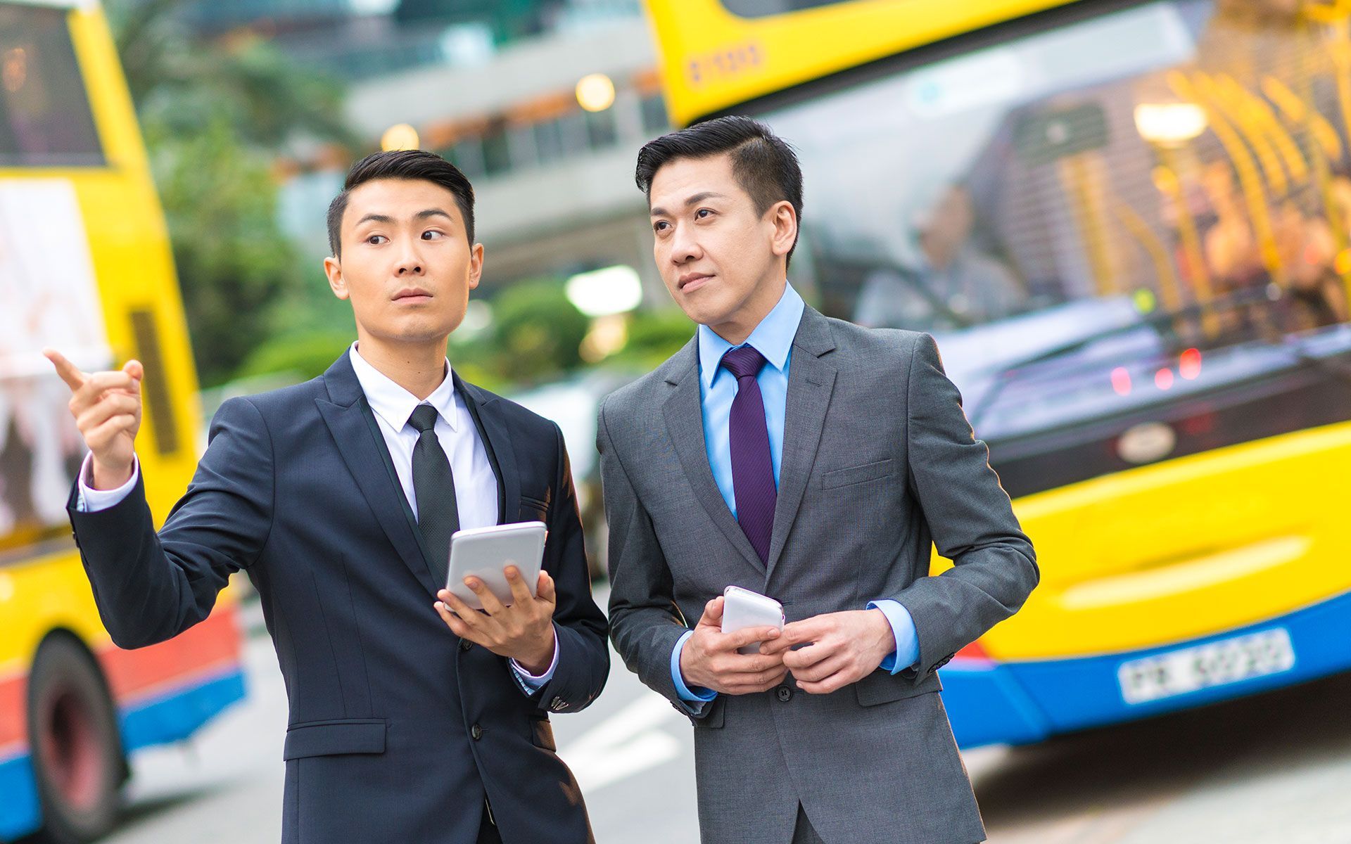 Two men in suits and ties are standing in front of a bus.