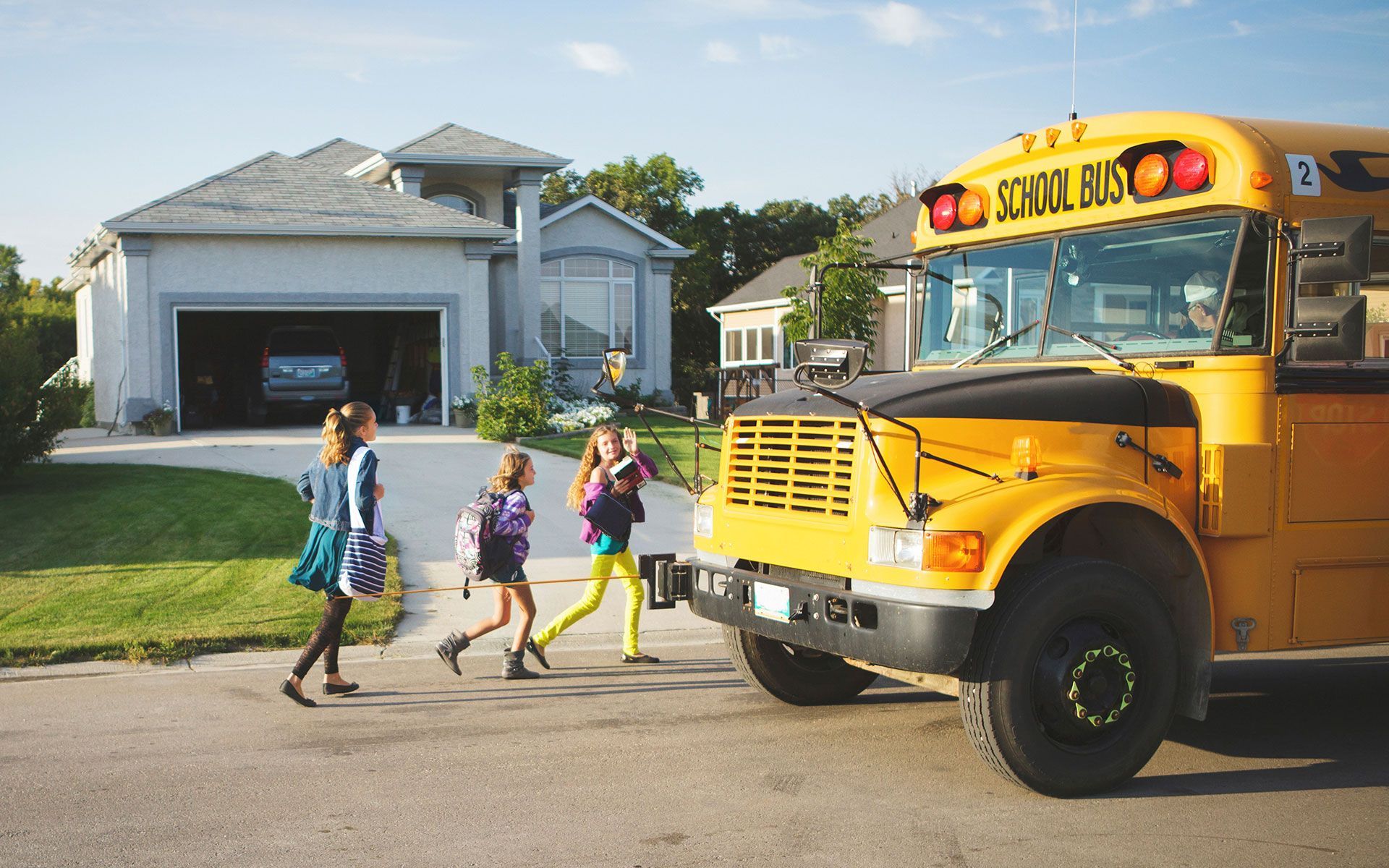 A group of children are walking towards a yellow school bus.