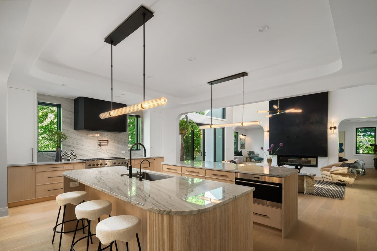 A kitchen with a large island and stools in it.