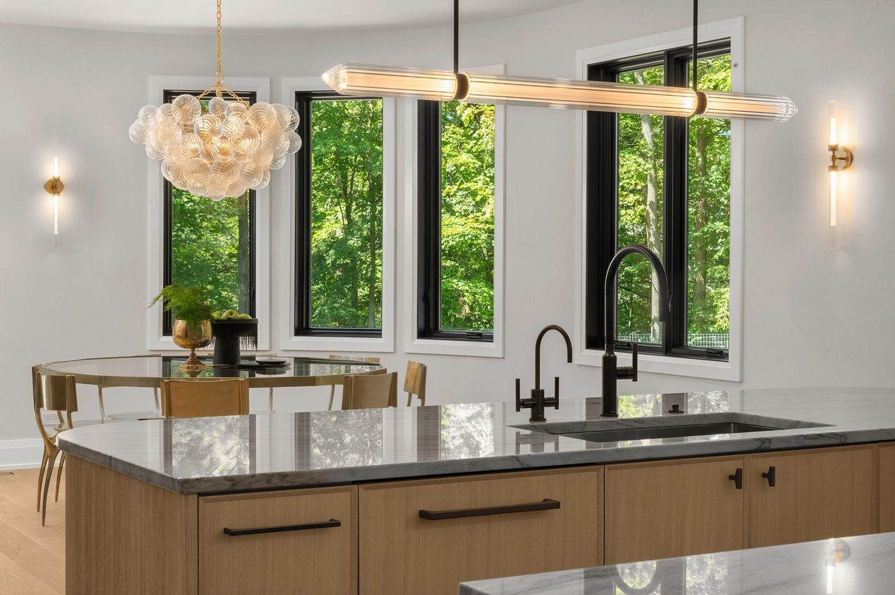 A kitchen with a large island , sink , and chandelier.