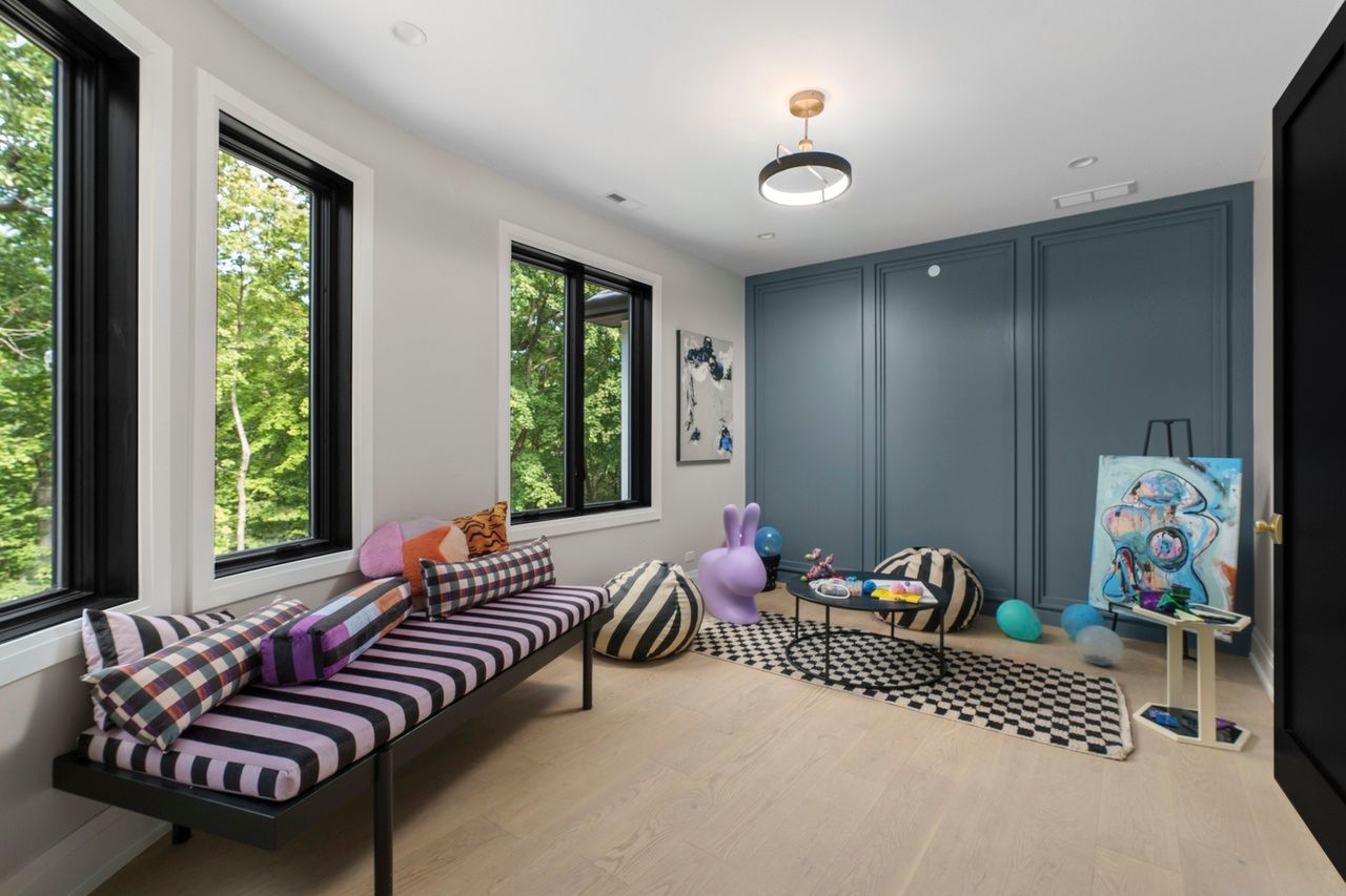 A living room with a couch , chairs , balloons and a painting on the wall.