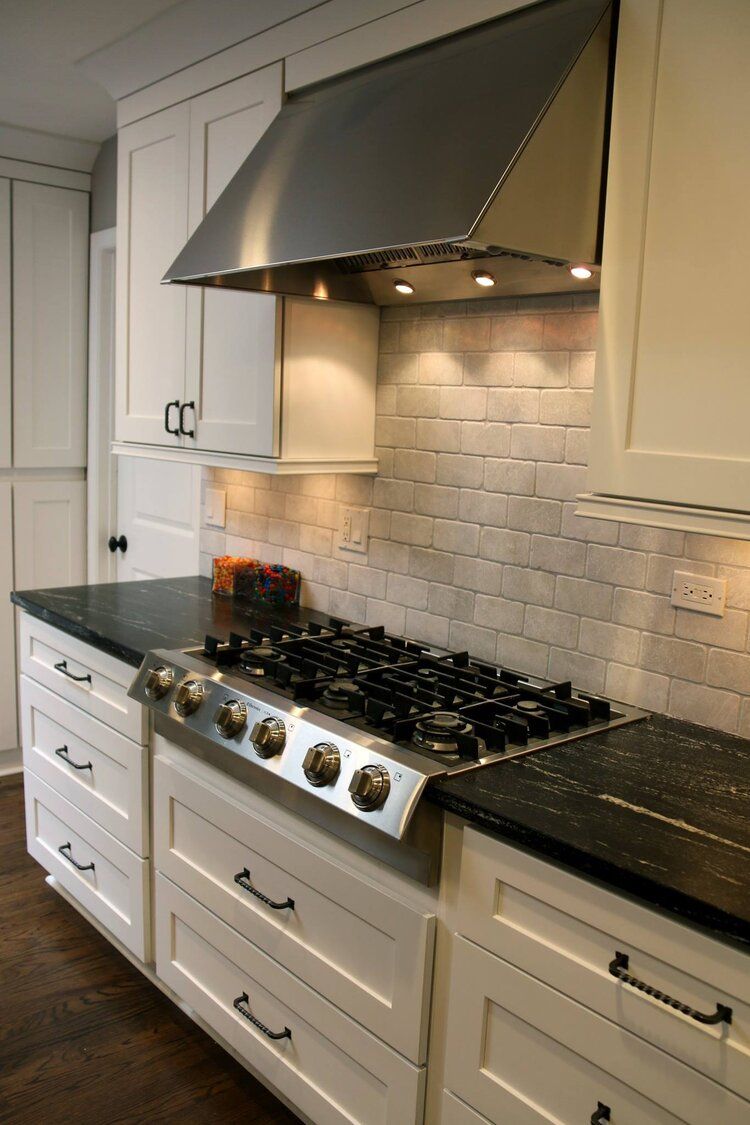 A kitchen with a stove top oven and black counter tops