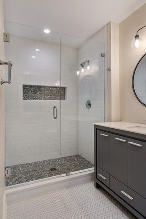A bathroom with a walk in shower , sink and mirror.