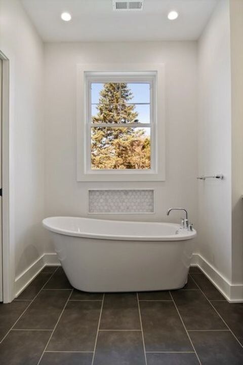 A bathroom with a bathtub and a window.