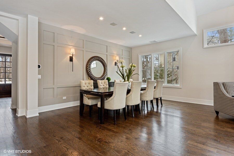 A dining room with a table and chairs and a mirror on the wall.