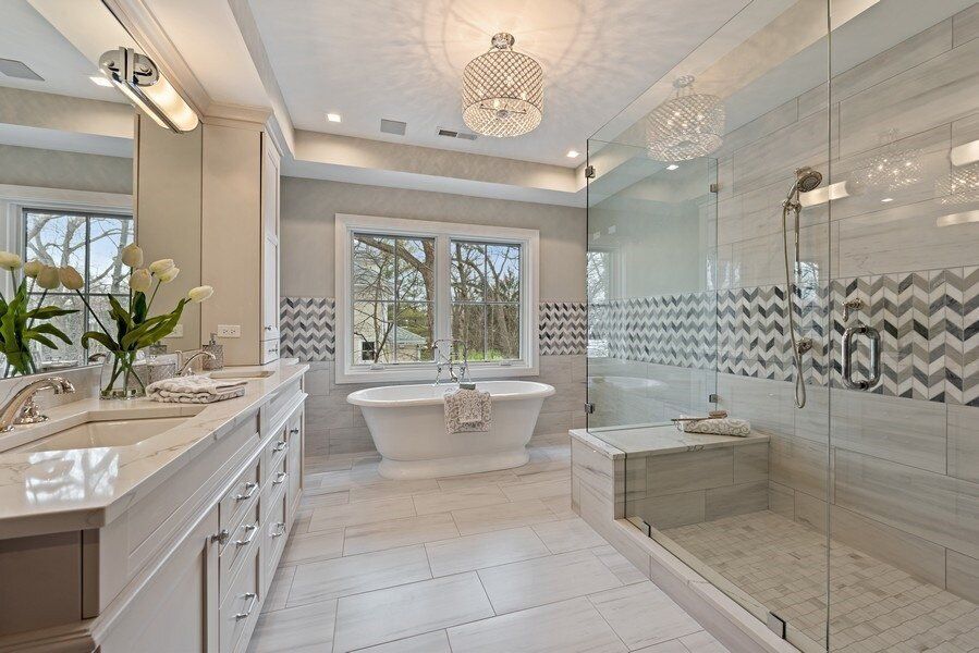 A bathroom with a bathtub , sinks , and a walk in shower.