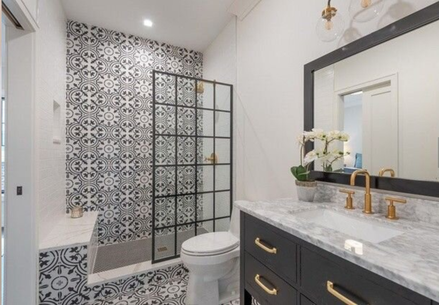 A bathroom with a toilet , sink , mirror and walk in shower.