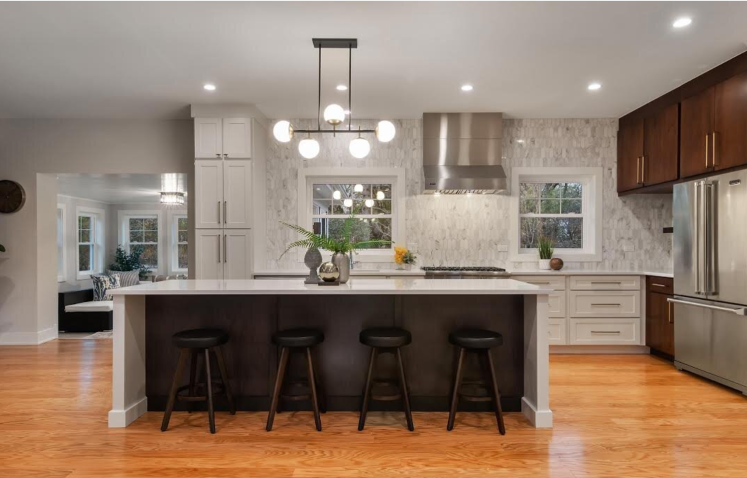 A kitchen with stools and a large island in the middle.