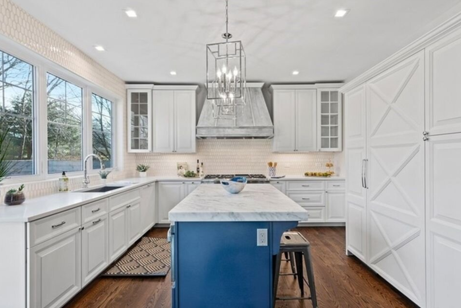 A kitchen with white cabinets and a blue island.