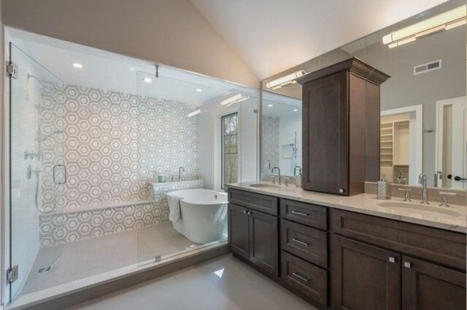 A bathroom with two sinks , a tub , and a walk in shower.