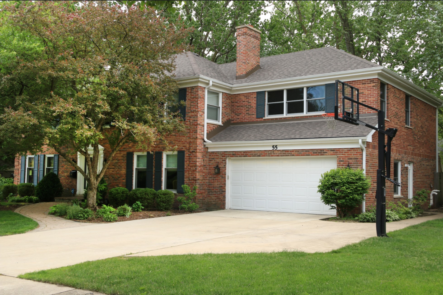 A brick house with a white garage door and a basketball hoop in front of it