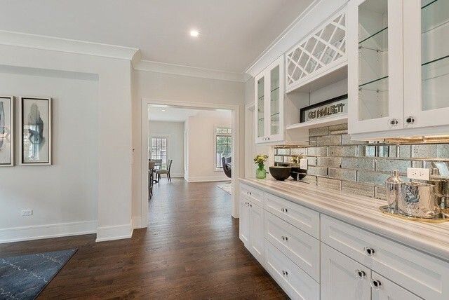 A kitchen with white cabinets and hardwood floors and a wine rack.