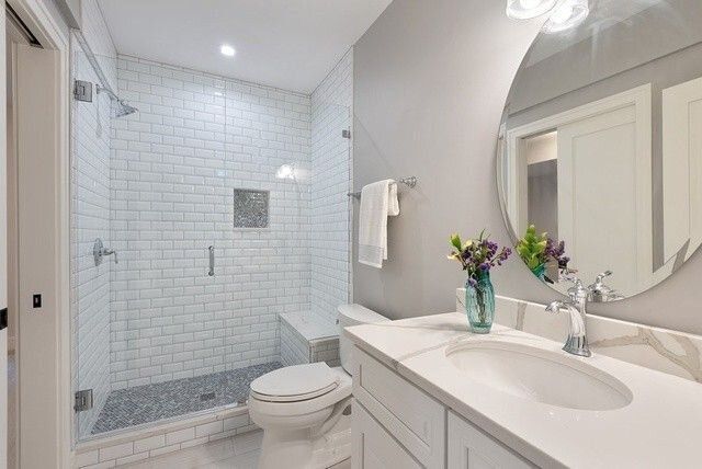 A bathroom with a toilet , sink , shower and mirror.