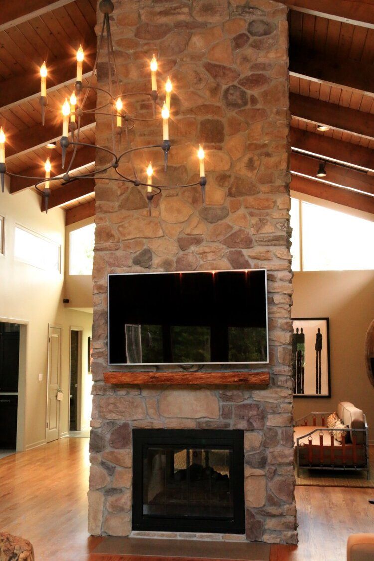 A living room with a stone fireplace and a flat screen tv