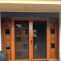 A double wooden door with glass panels and sidelights set in a wall with a dark blue lintel.