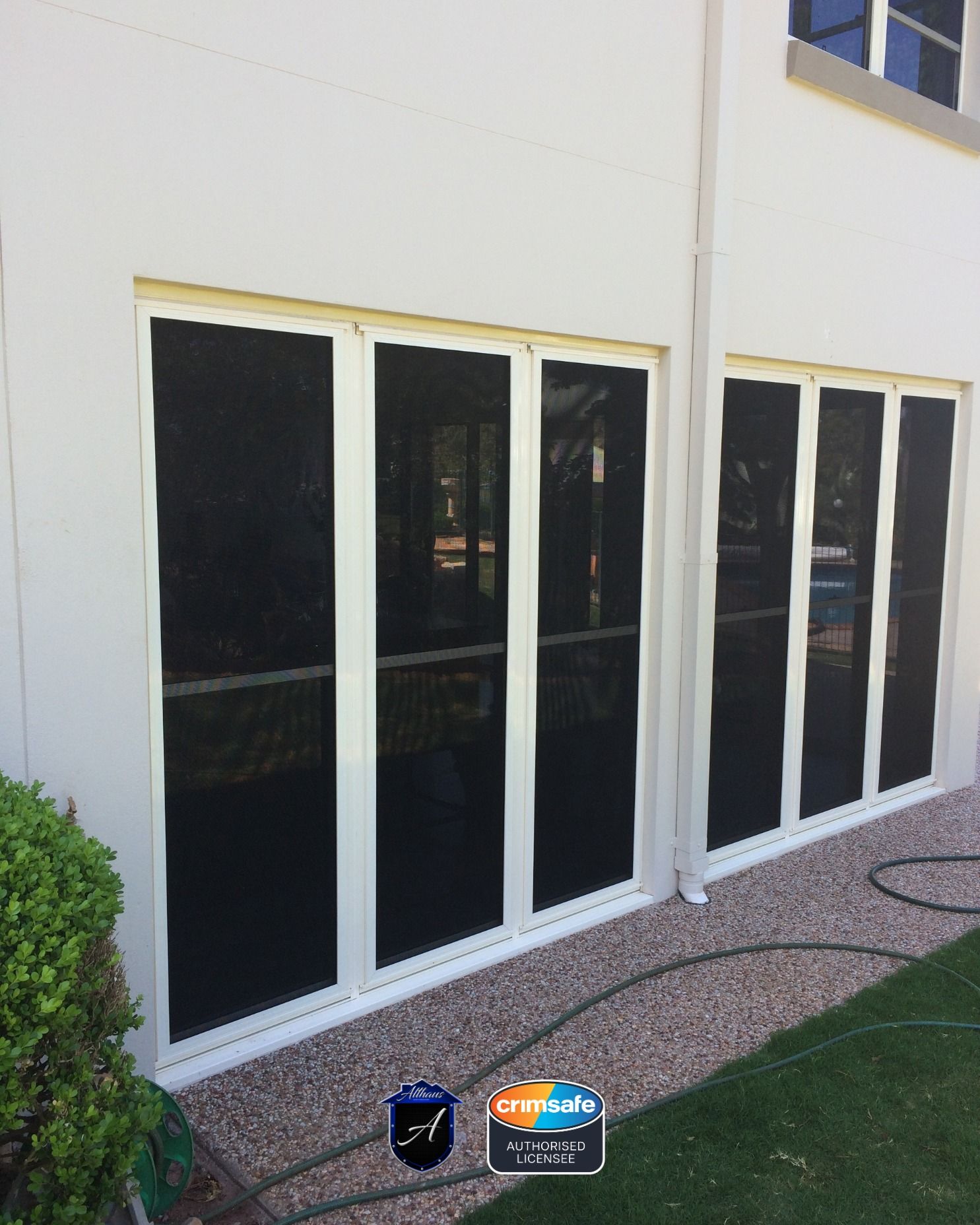 White frames with black mesh security screens installed on exterior glass sliding doors of a home.