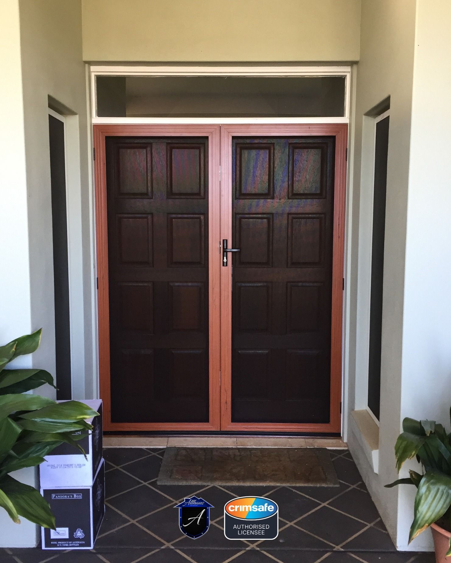 A pair of dark brown paneled doors with light wooden frames, centered in a tiled entryway with a transom window above.