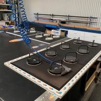 A workstation with a large vacuum-suction table used for securing materials, featuring numerous circular suction cups.