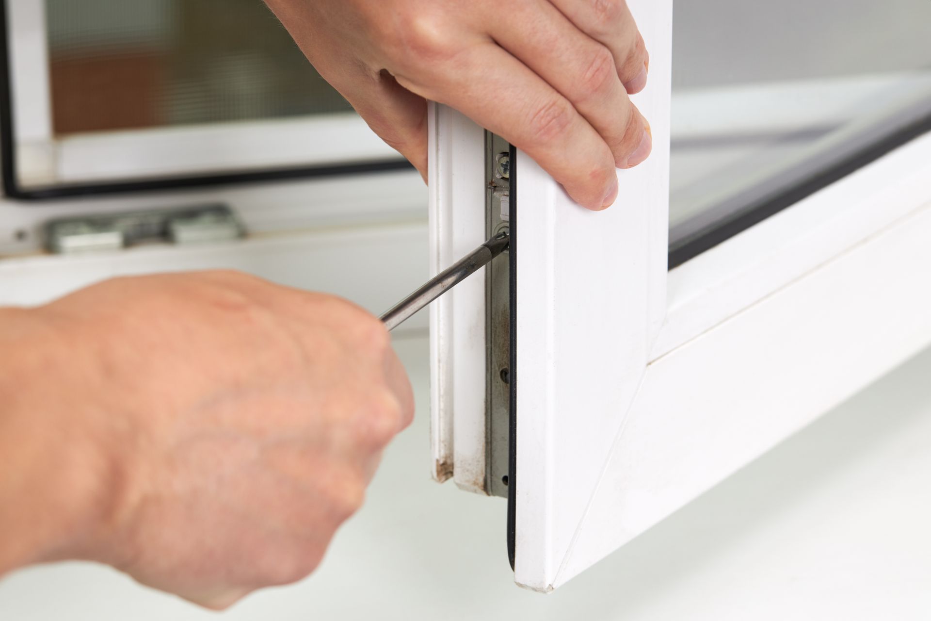 A person’s hands using a screwdriver to install a window.