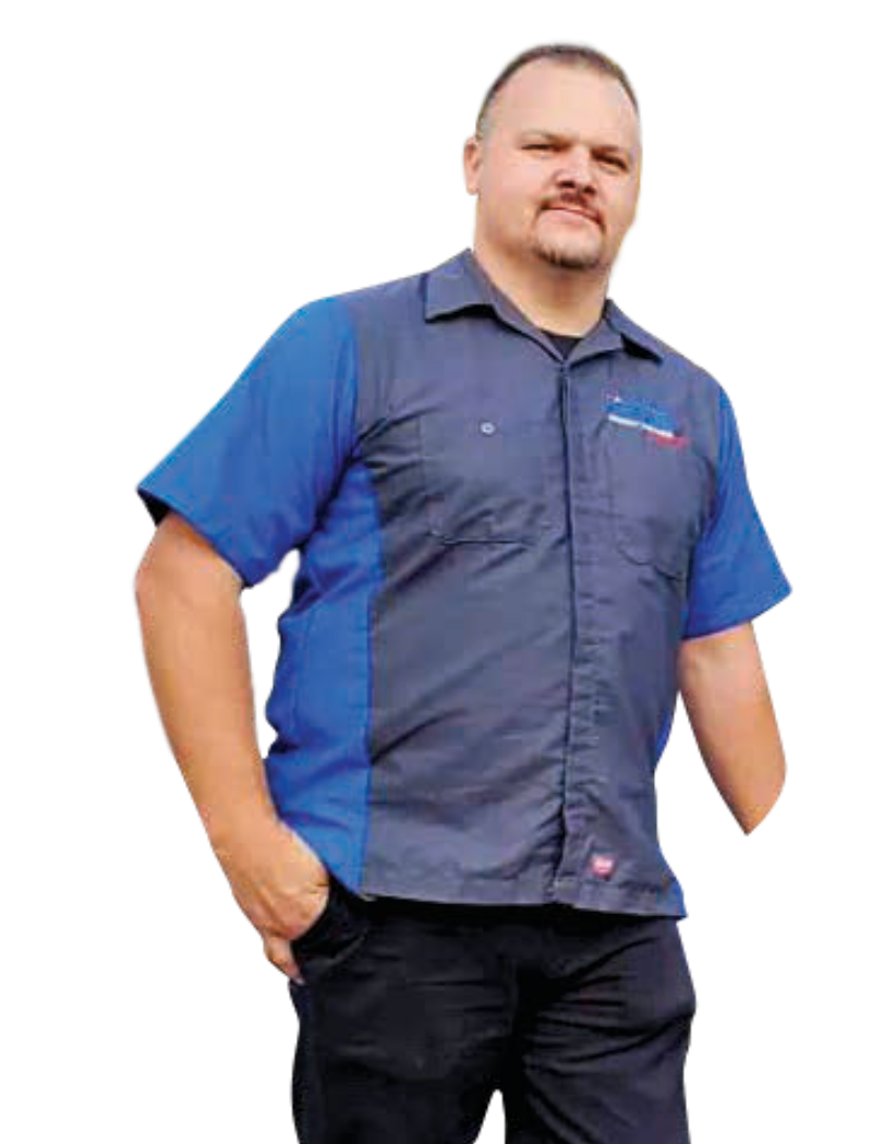 A person standing against a white background, wearing a two-toned blue and navy work shirt and dark pants, with one arm.